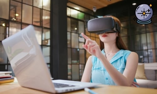 Vrouw met VR-bril wijst in de lucht terwijl ze aan een bureau met laptop zit in een moderne kantoorruimte.